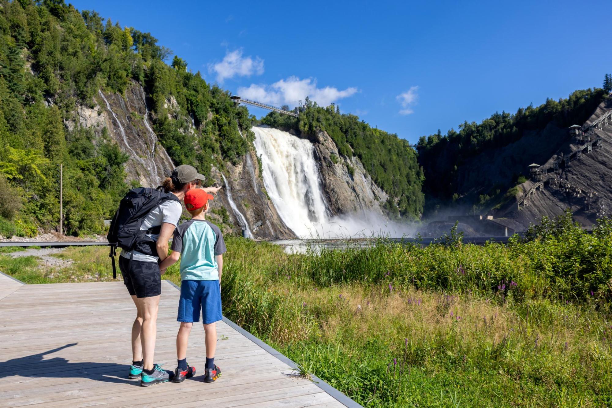 A mother and son stand in front of Montmorency Falls