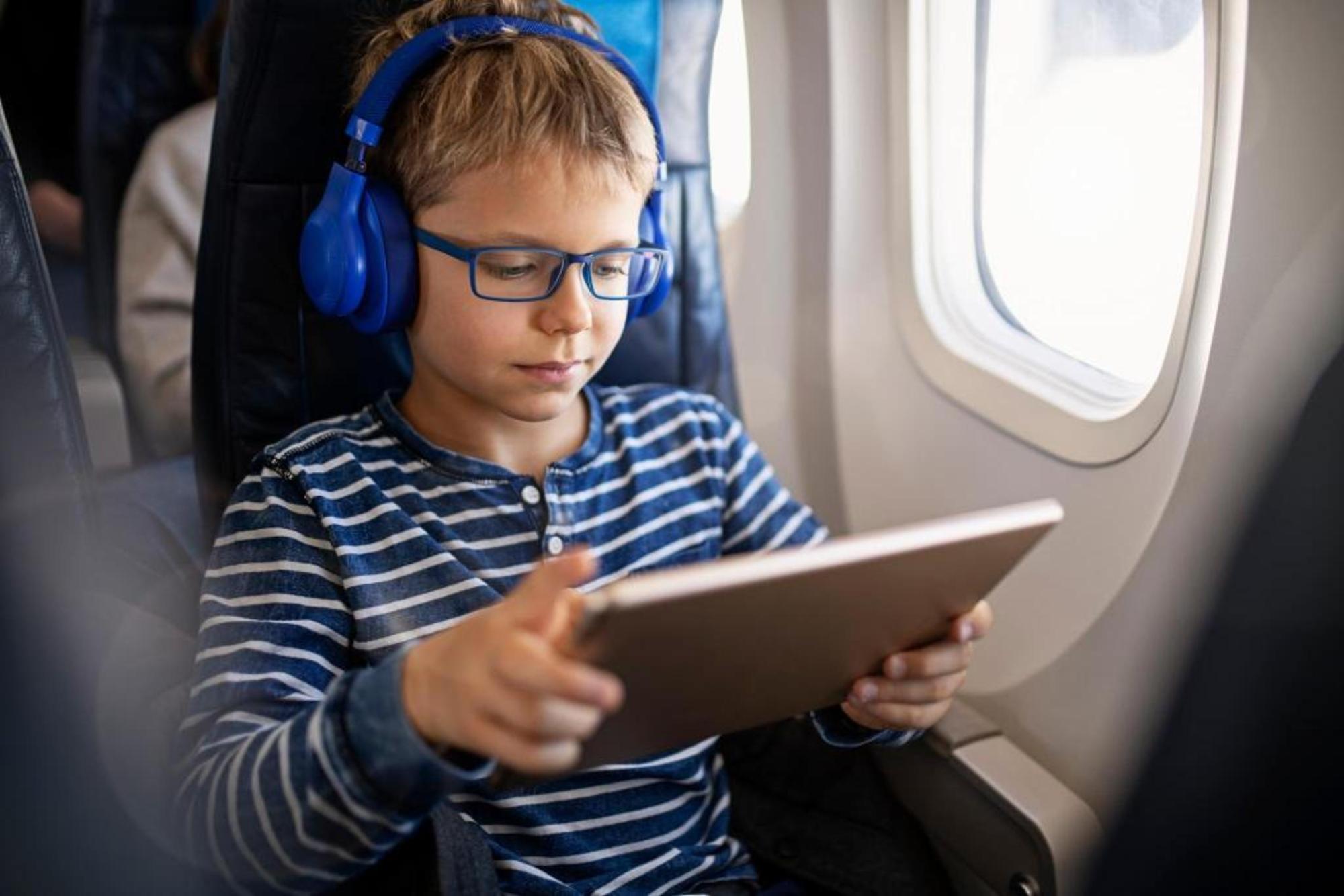 A child on a plane using his tablet during a flight