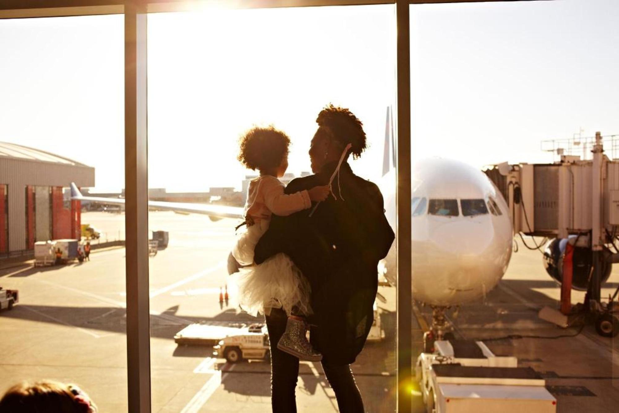 A parent carrying a child with a plane in the back