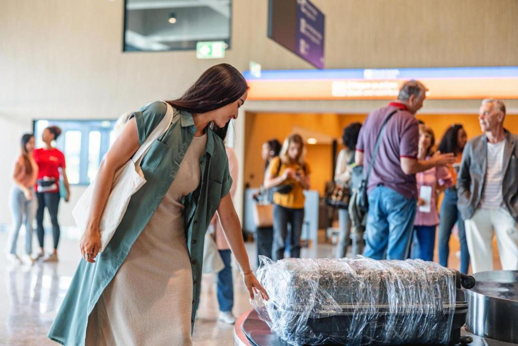 A woman grabbing her wrapped luggage from the luggage belt