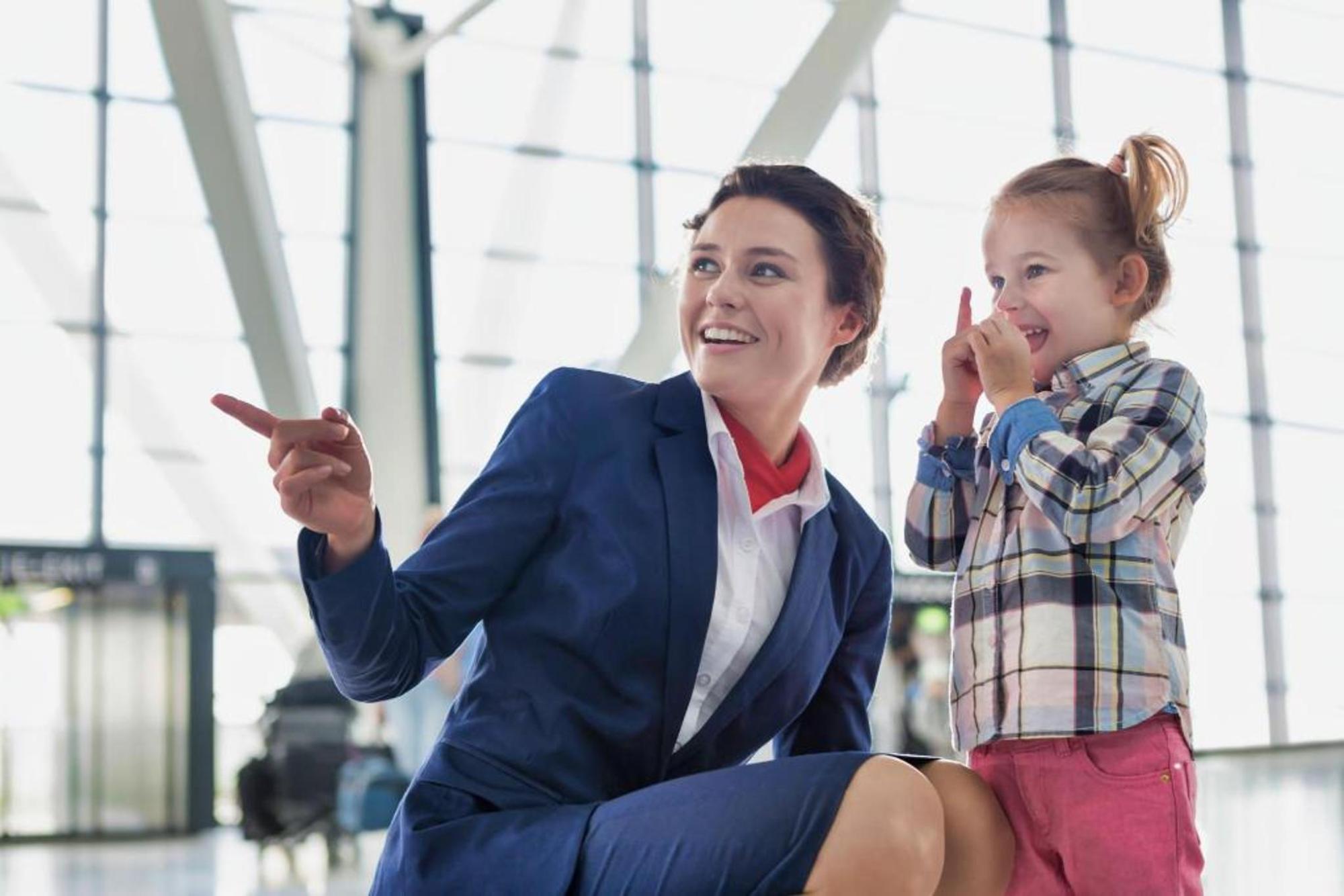 A flight attendant and a child smiling at the airport