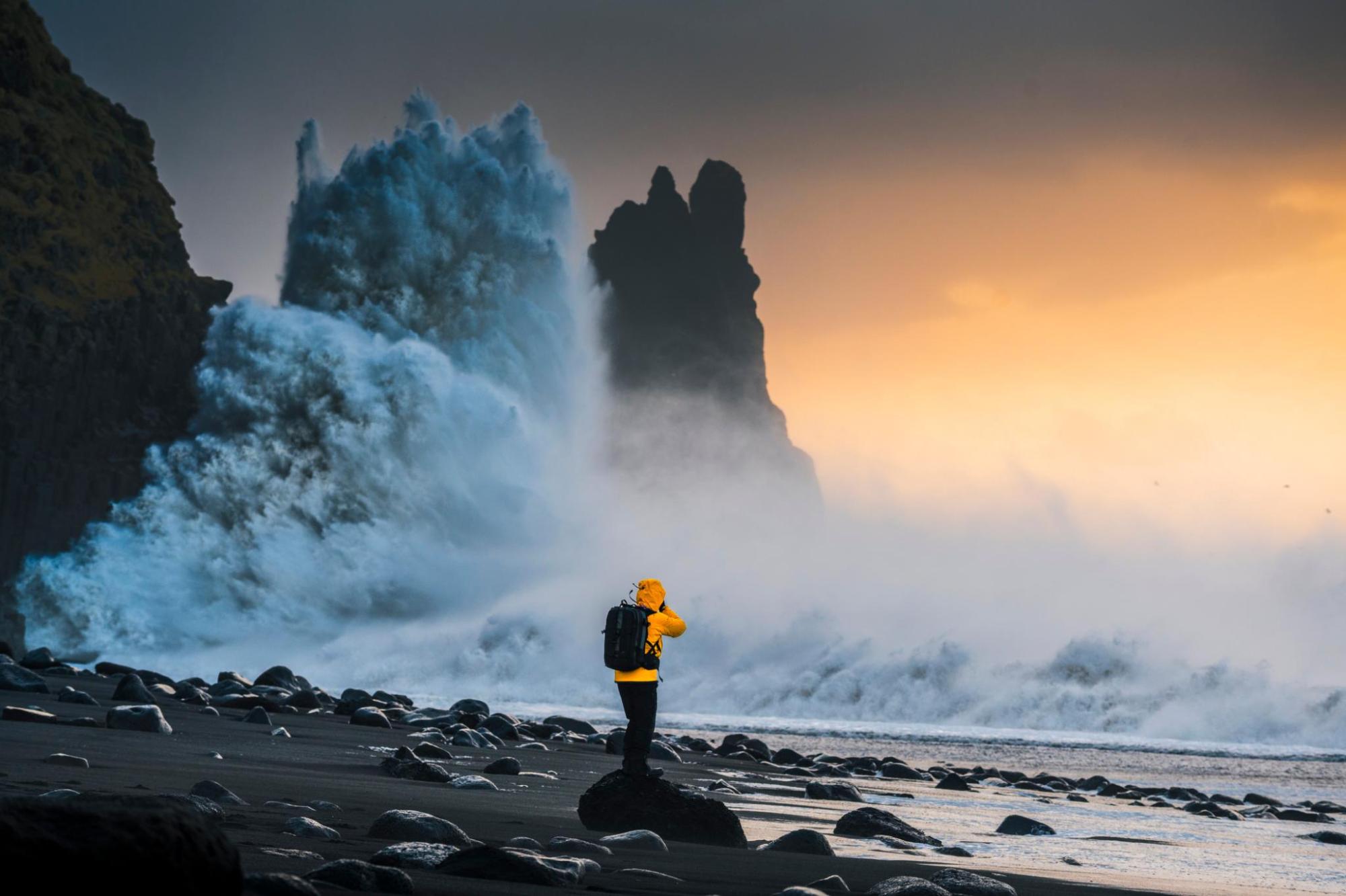 Visitor standing on a black sand beach as waves crash