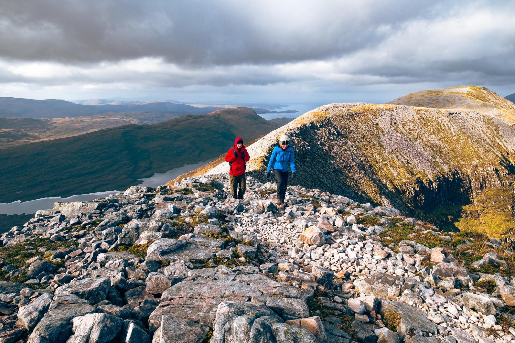 Two hikers walking along a rocky mountain ridge
