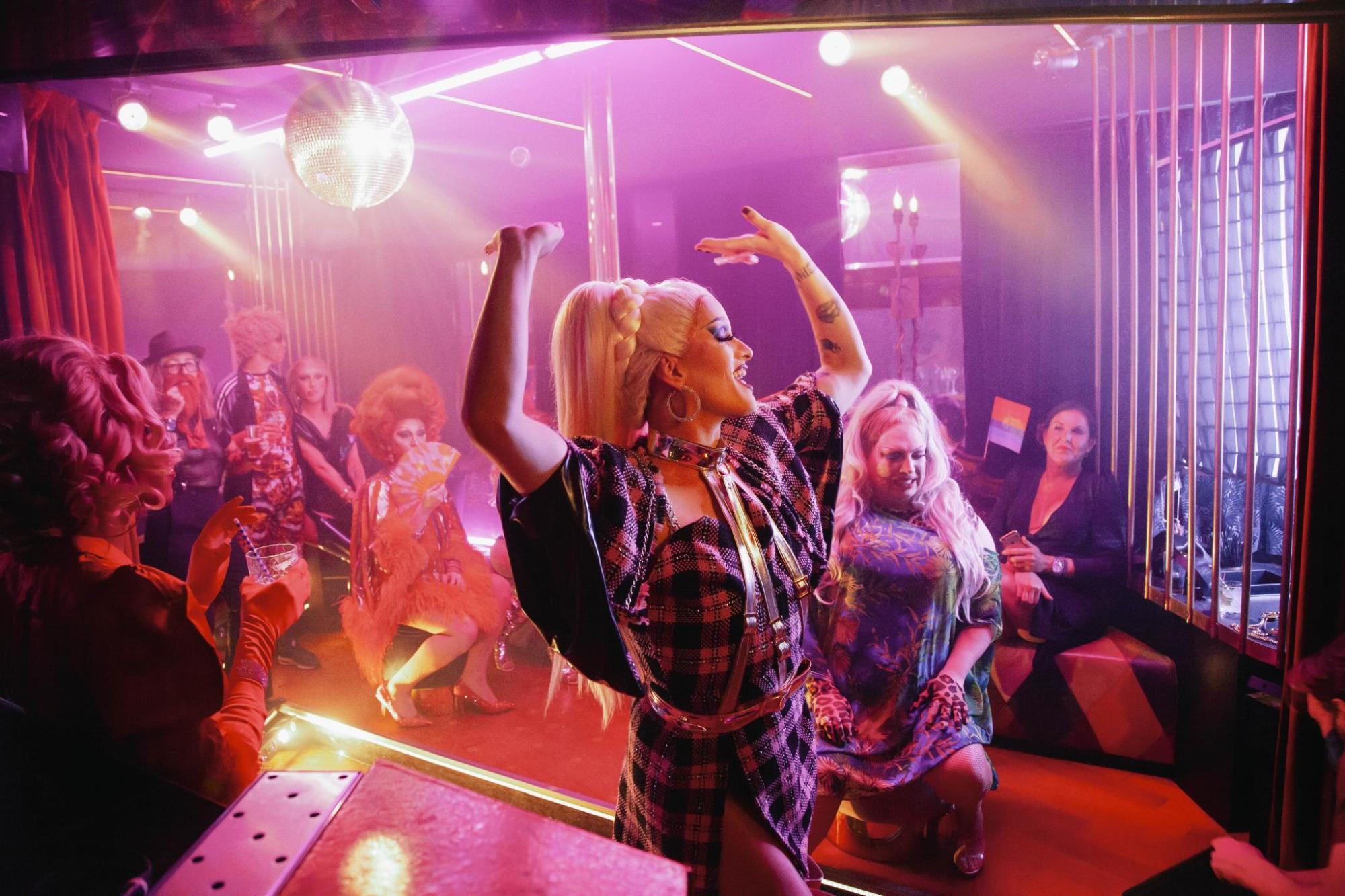 Drag performer dancing under lights in a lively nightclub