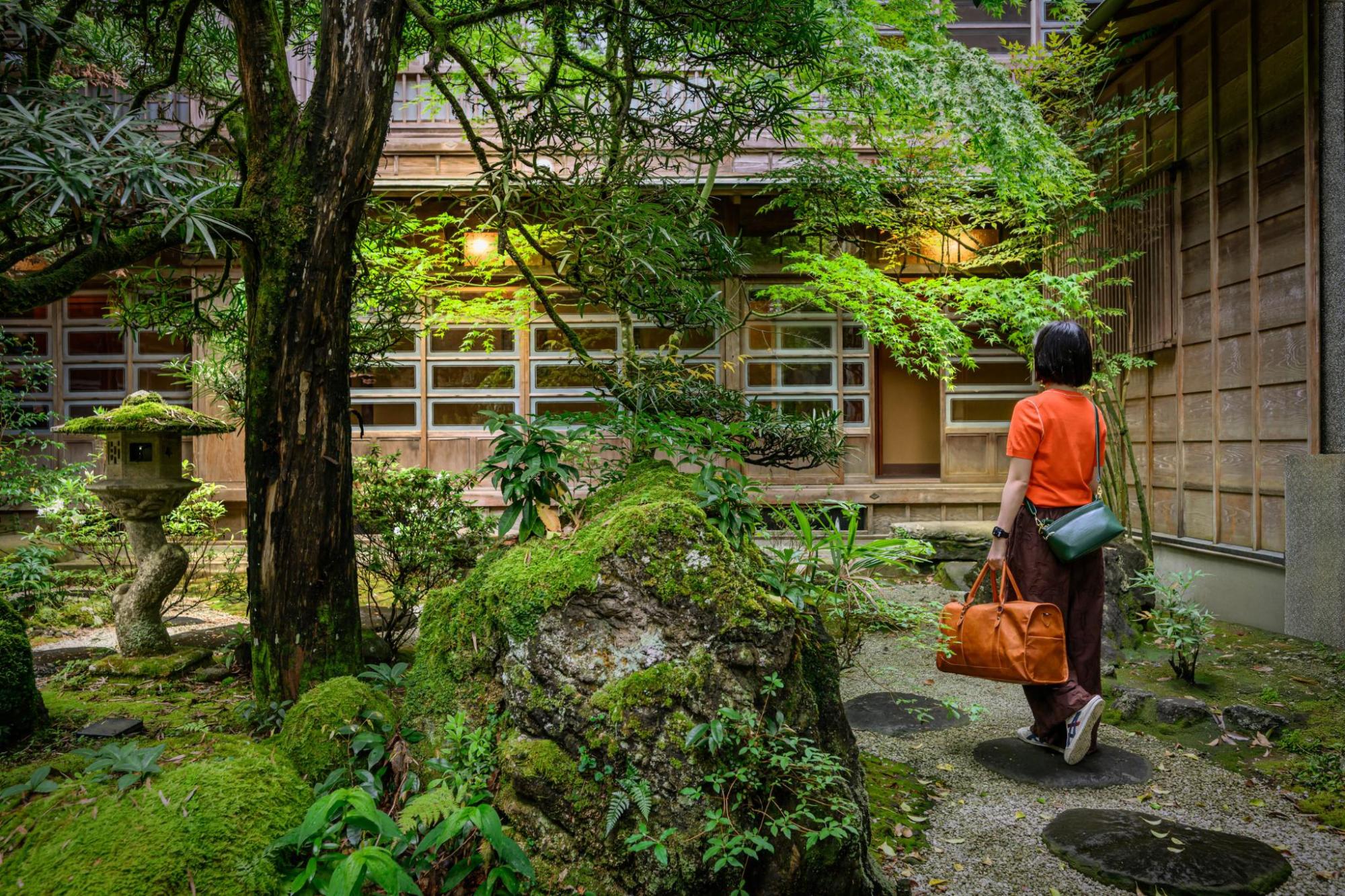 Guest arriving at a lush traditional Japanese inn
