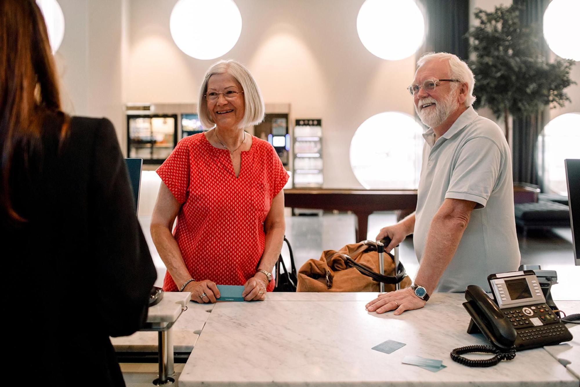 A woman and man are positioned at a hotel front desk