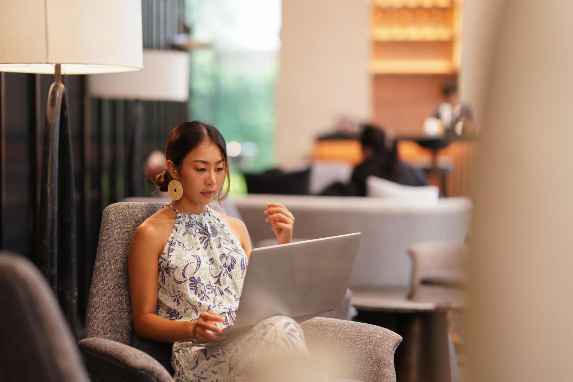 A woman sitting in a hotel lobby, using her laptop for work.