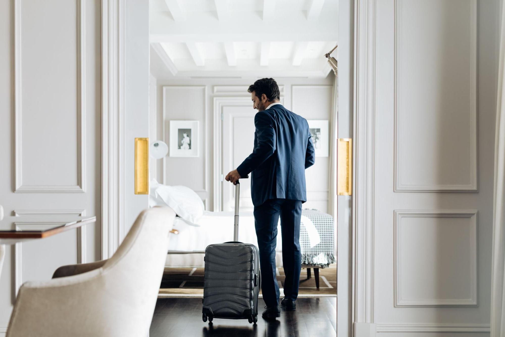 Guest entering a bright hotel room with suitcase