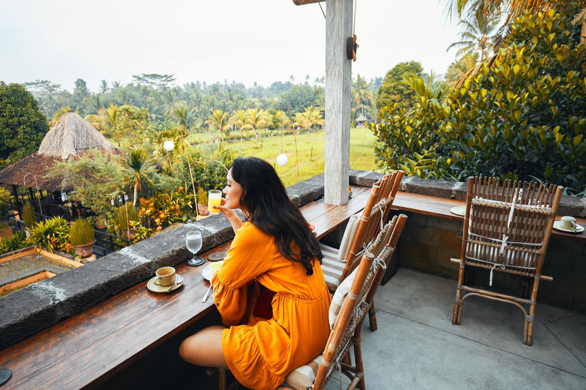 Woman relaxing on a terrace overlooking Bali's countryside.