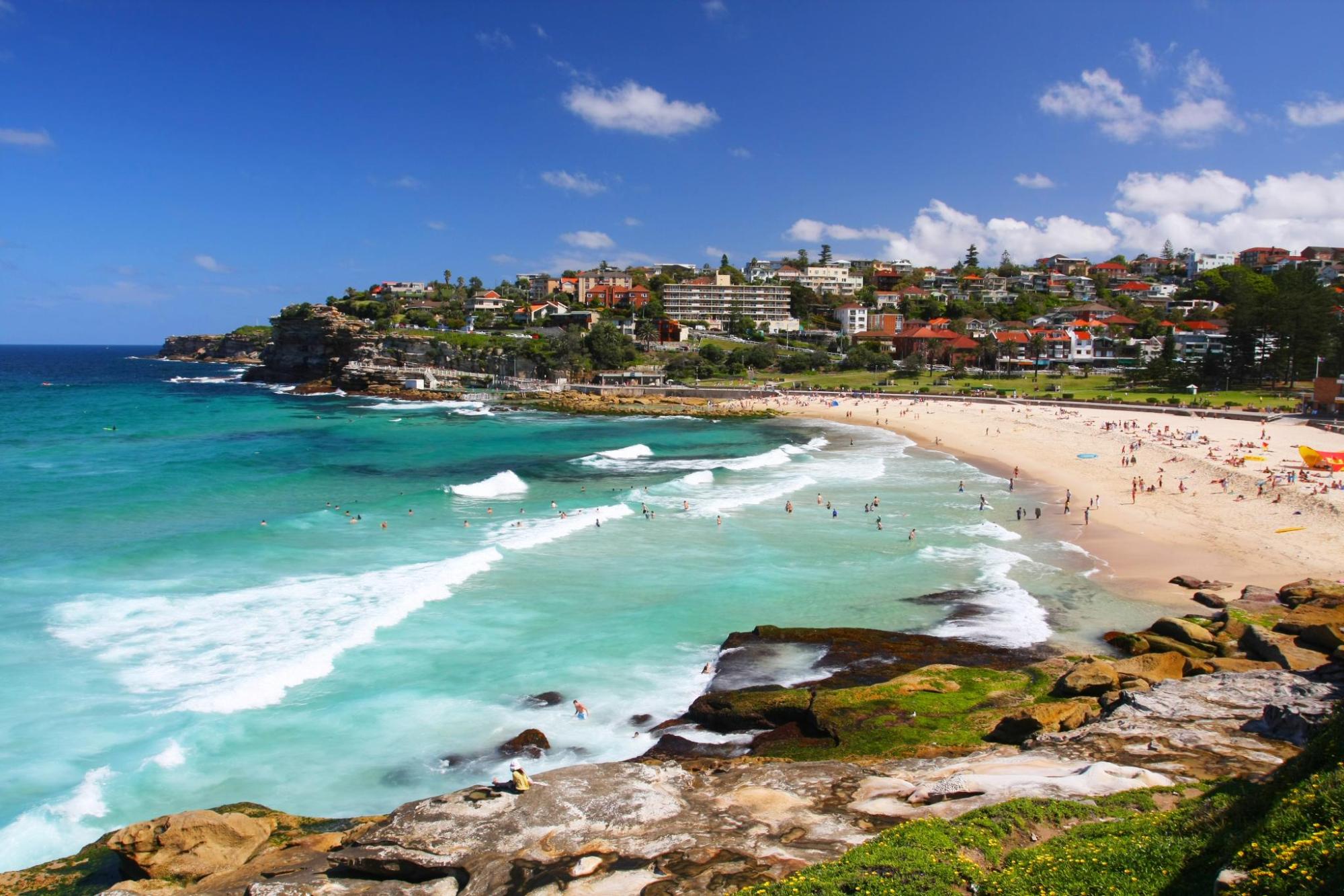 Turquoise waves roll onto a busy Bondi Beach.