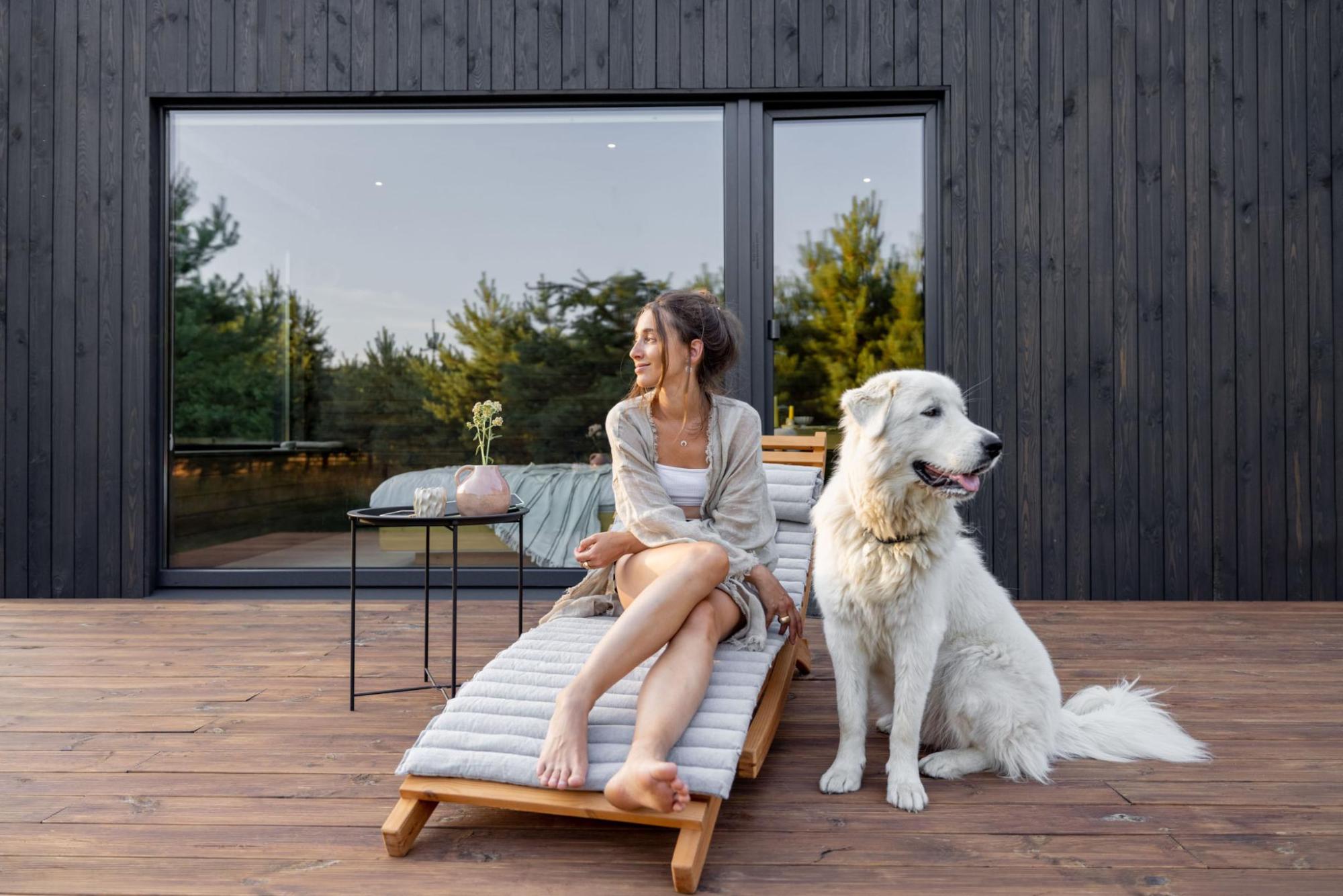 Woman relaxing on a cabin deck beside a large white dog 