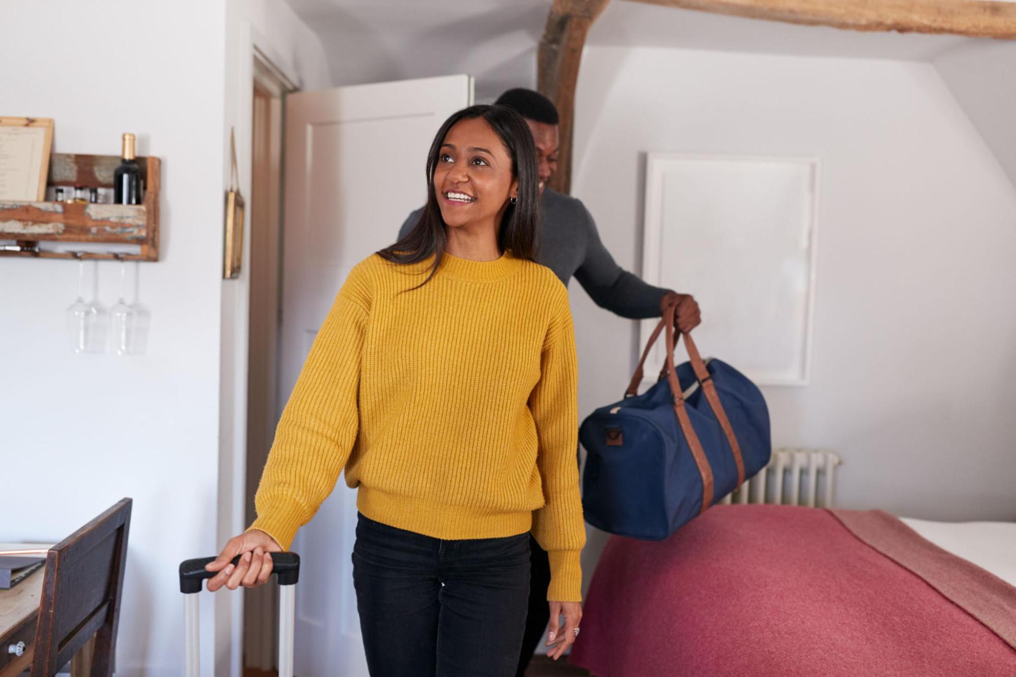 Zwei Gäste betreten ein Schlafzimmer und haben ihr Gepäck dabei