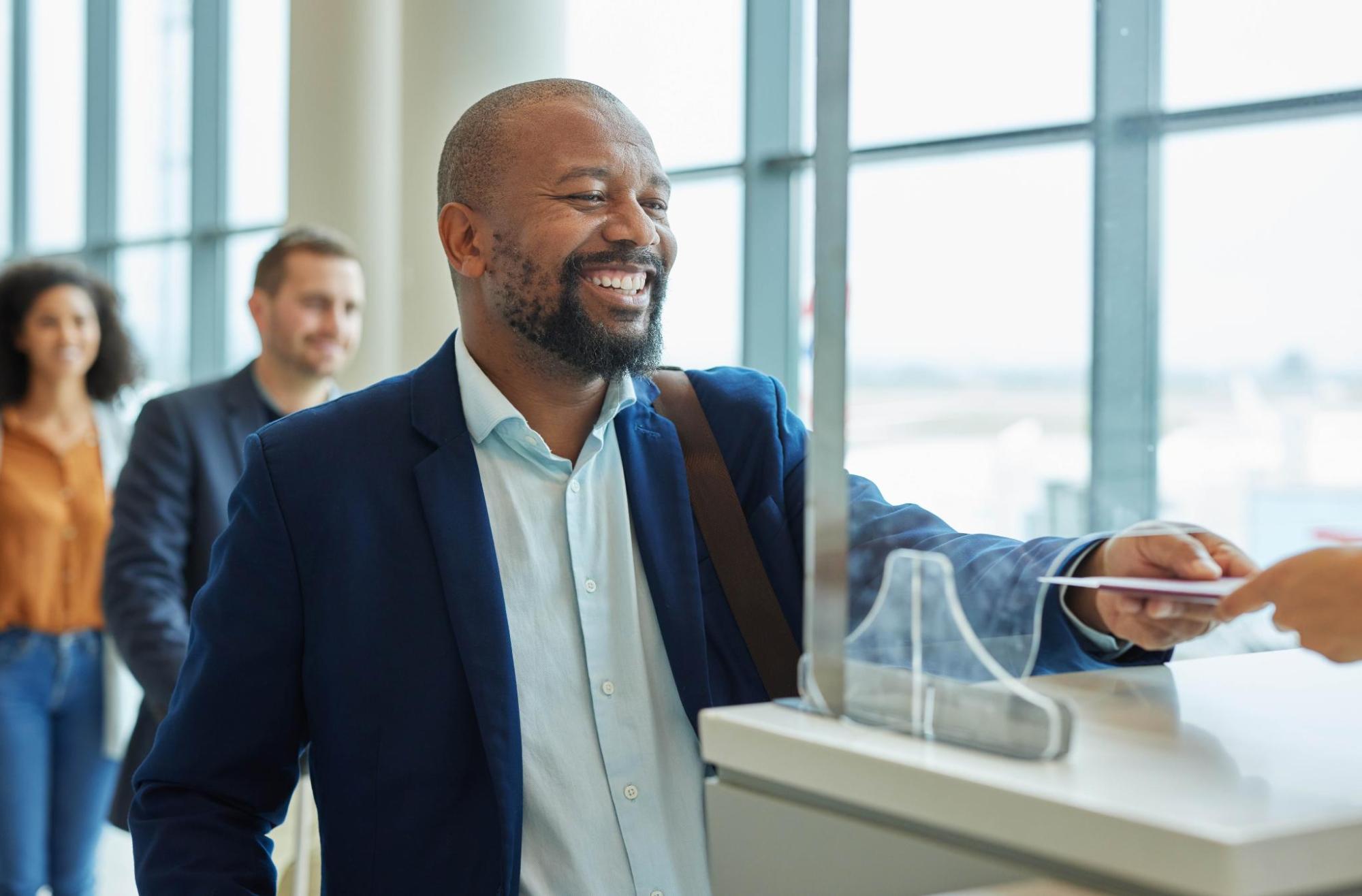 A person smiles while showing their travel document at an immigration checkpoint