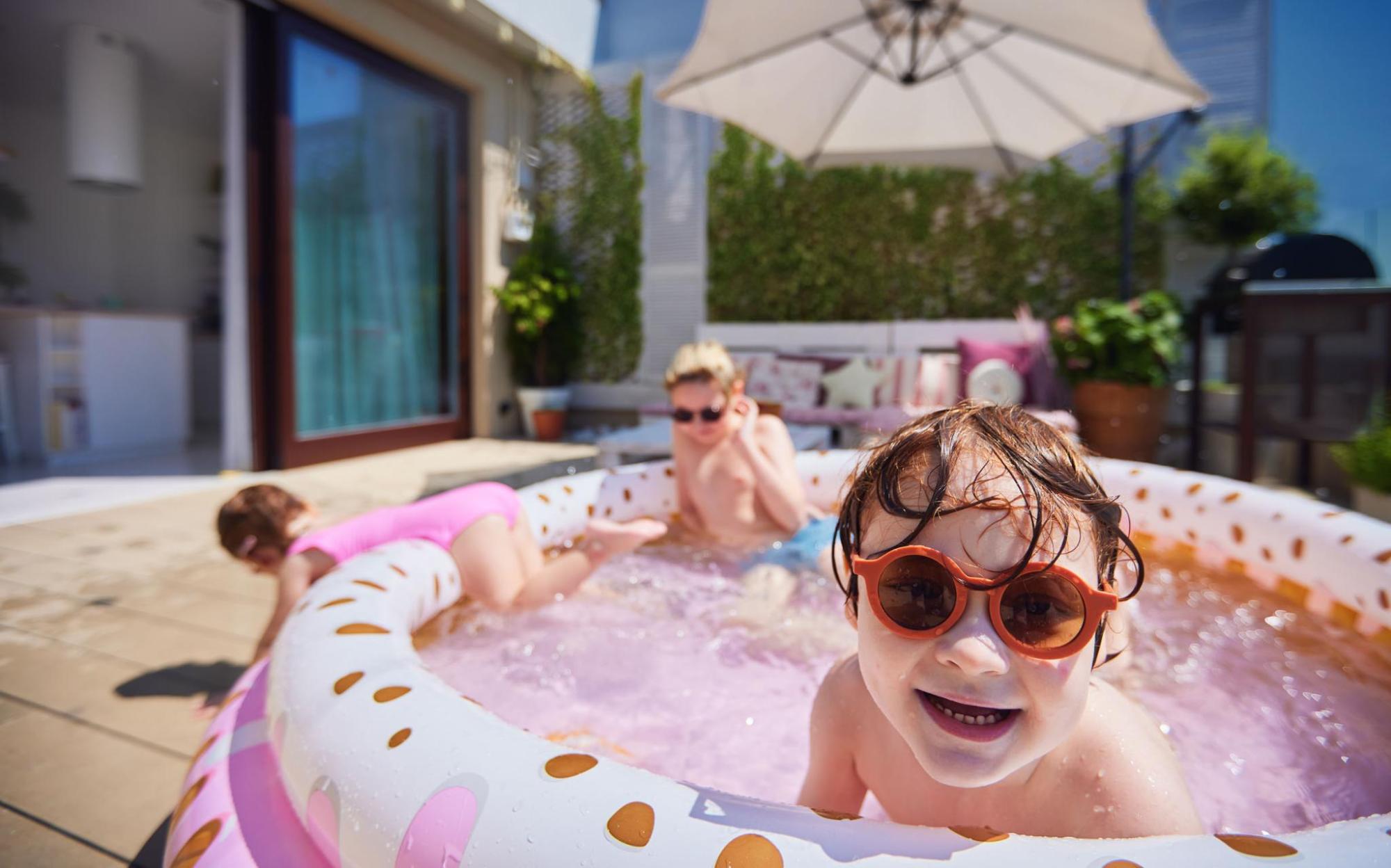 Three children in an inflatable pool on a terrace