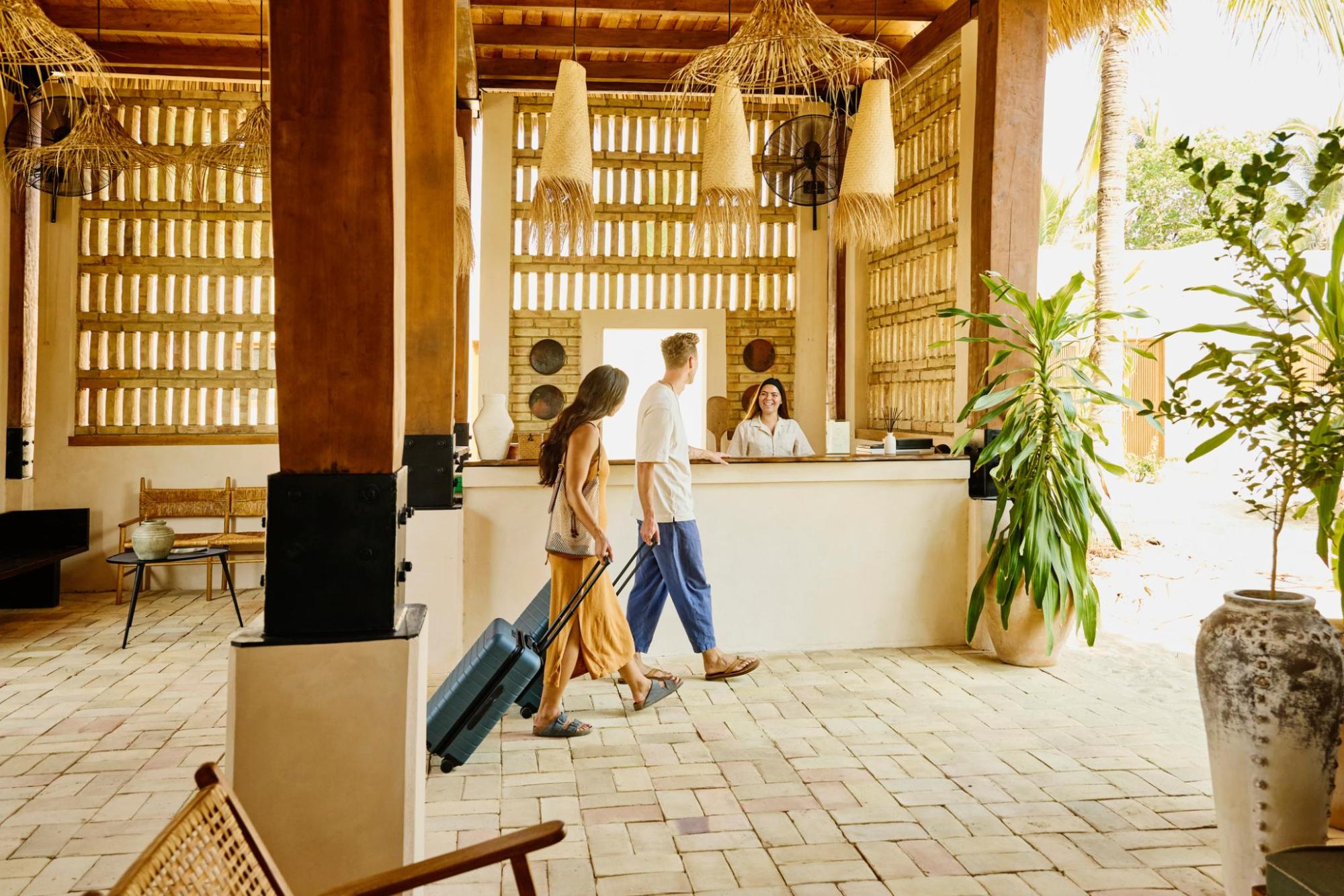Two guests walking through a hotel lobby with suitcases
