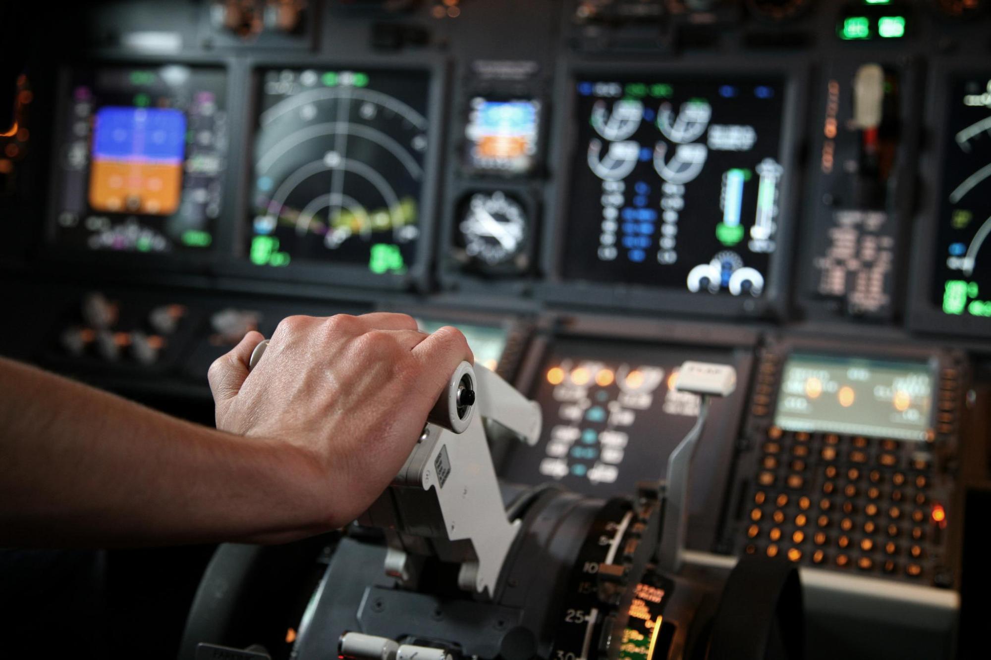 A pilot in a cockpit controls the aircraft using a joystick
