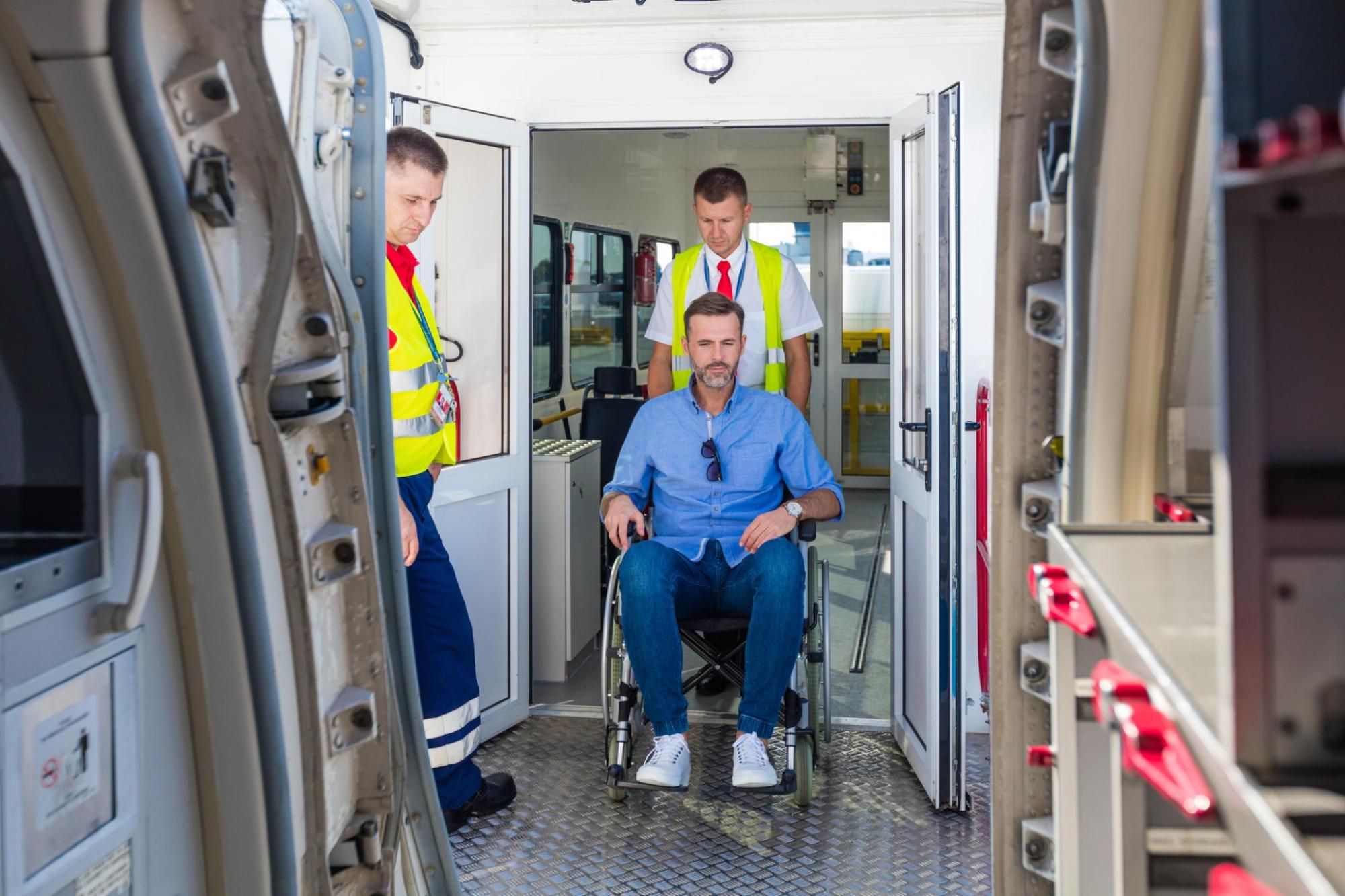 Ground crew help a passenger in a wheelchair board a plane