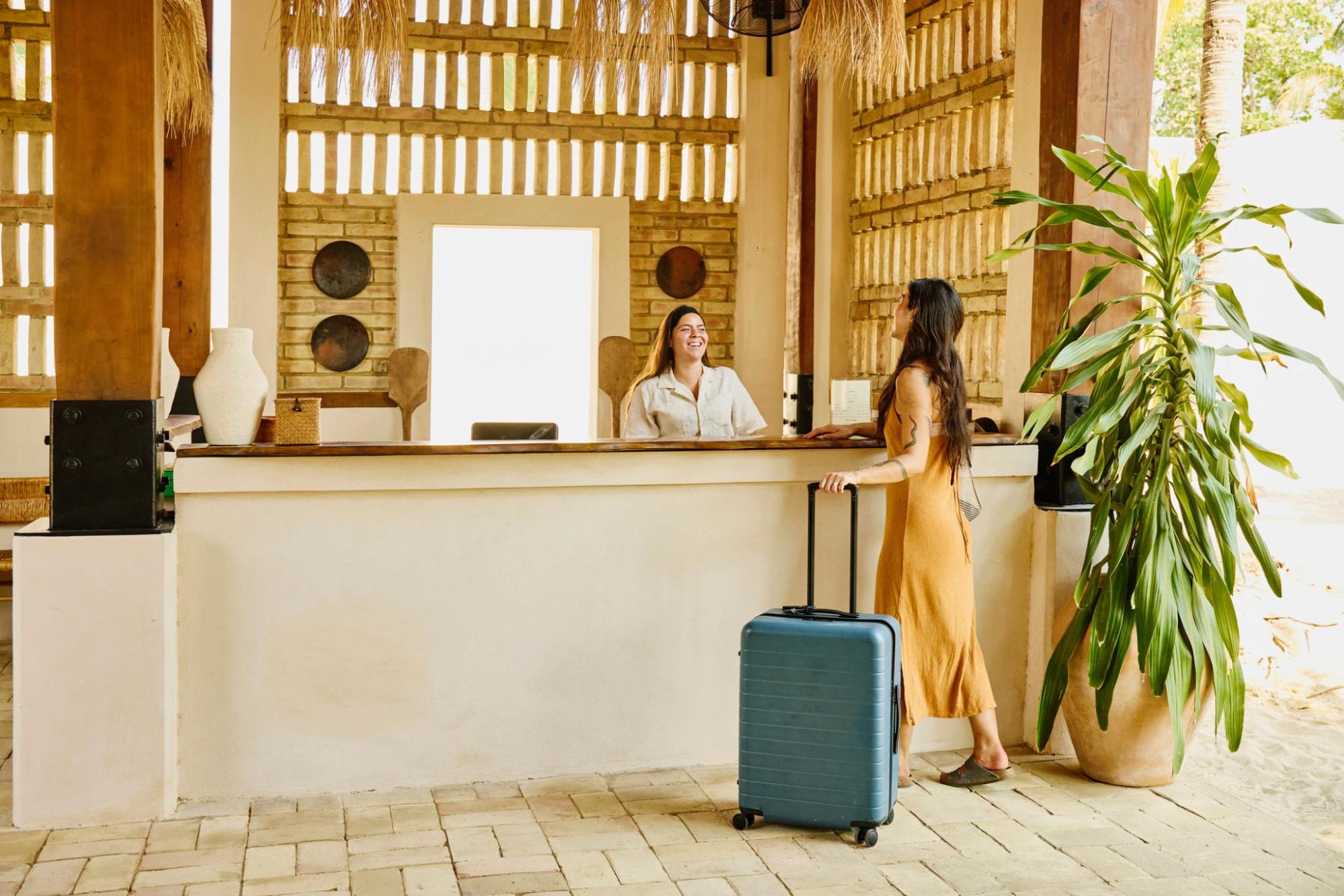 Traveller holds a suitcase while talking with the hotel staff