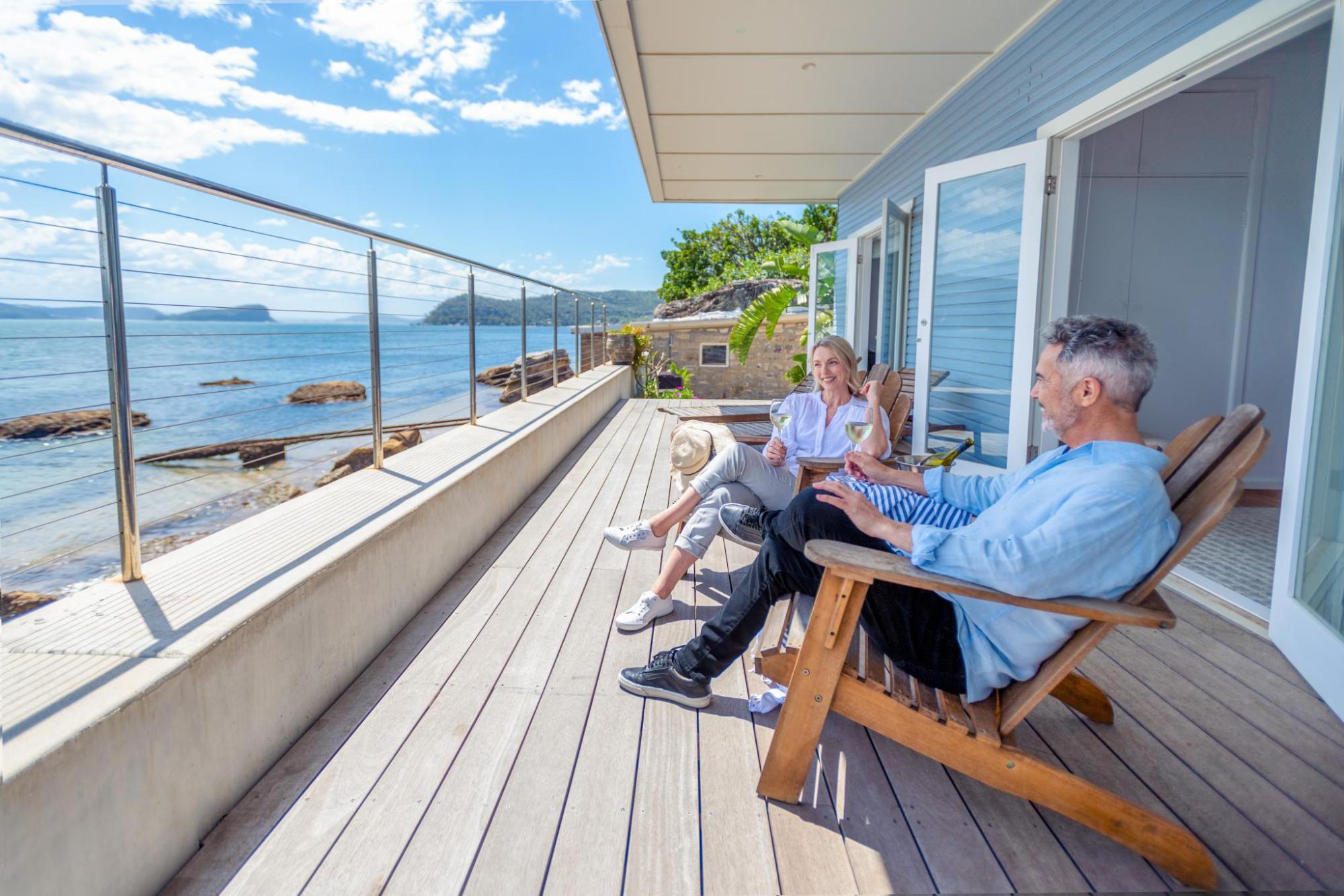 Couple relaxing on a coastal terrace with drinks and sea views outside a holiday stay 
