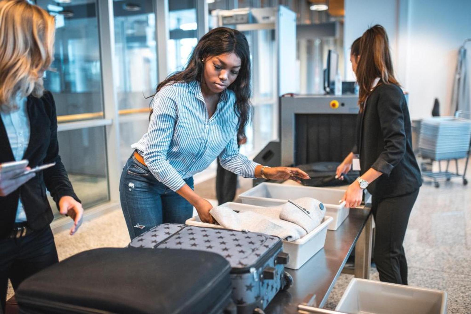 Une femme place ses effets personnels dans un bac avant le contrôle de sécurité à l’aéroport