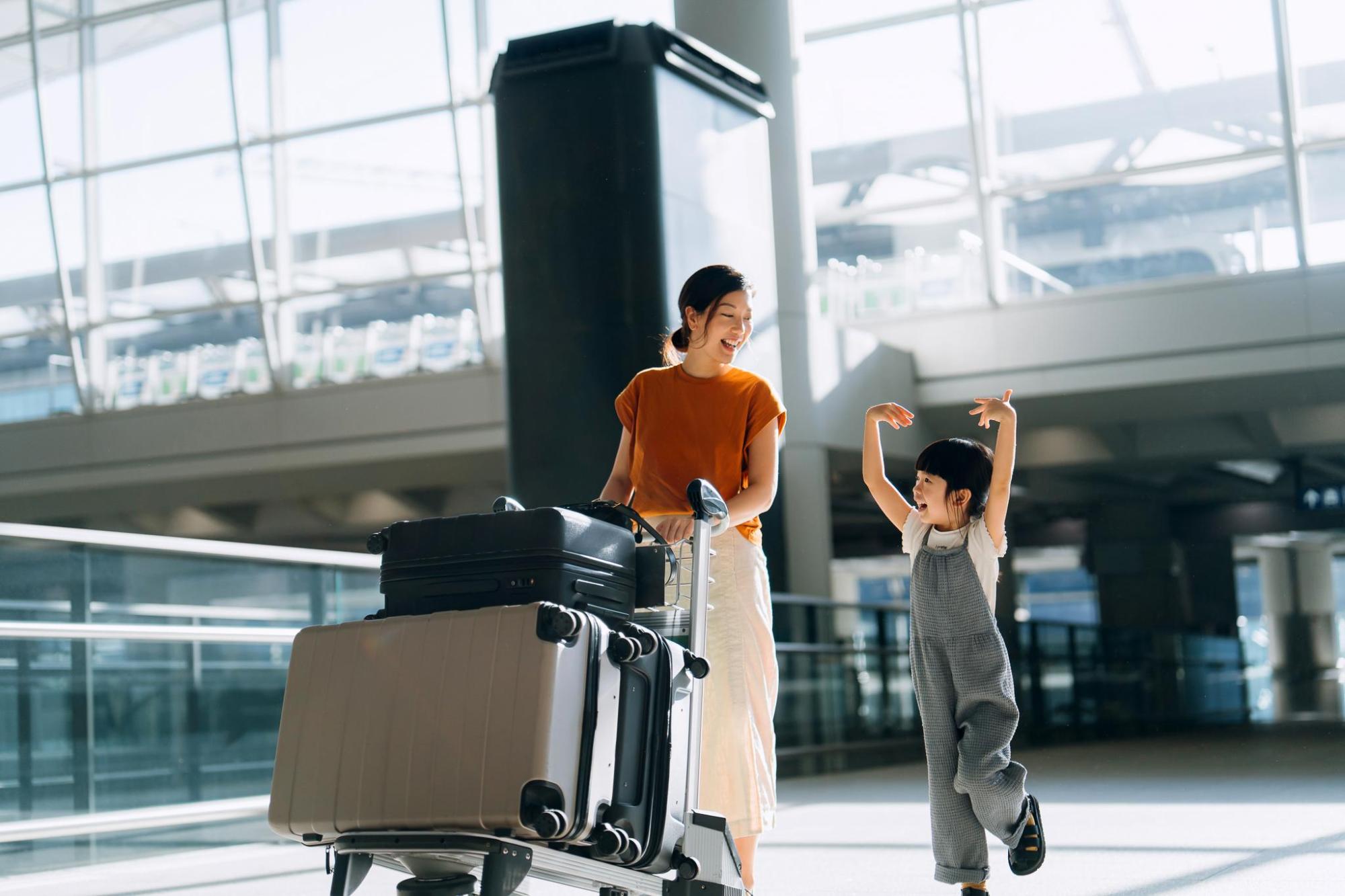 空港内で荷物を運ぶ旅行者と子ども