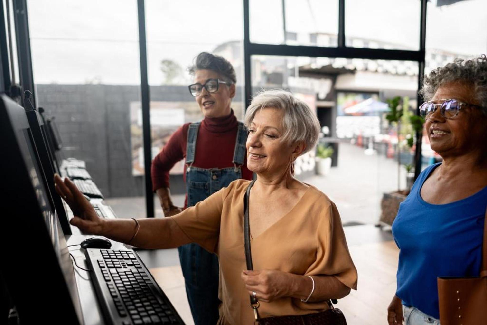 Three women standing using a public computer
