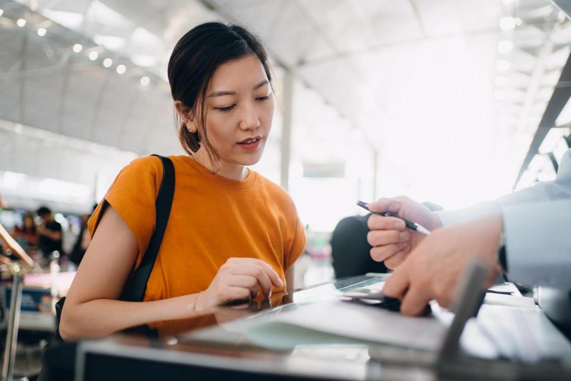 Traveller speaking with an airport staff member at a service desk
