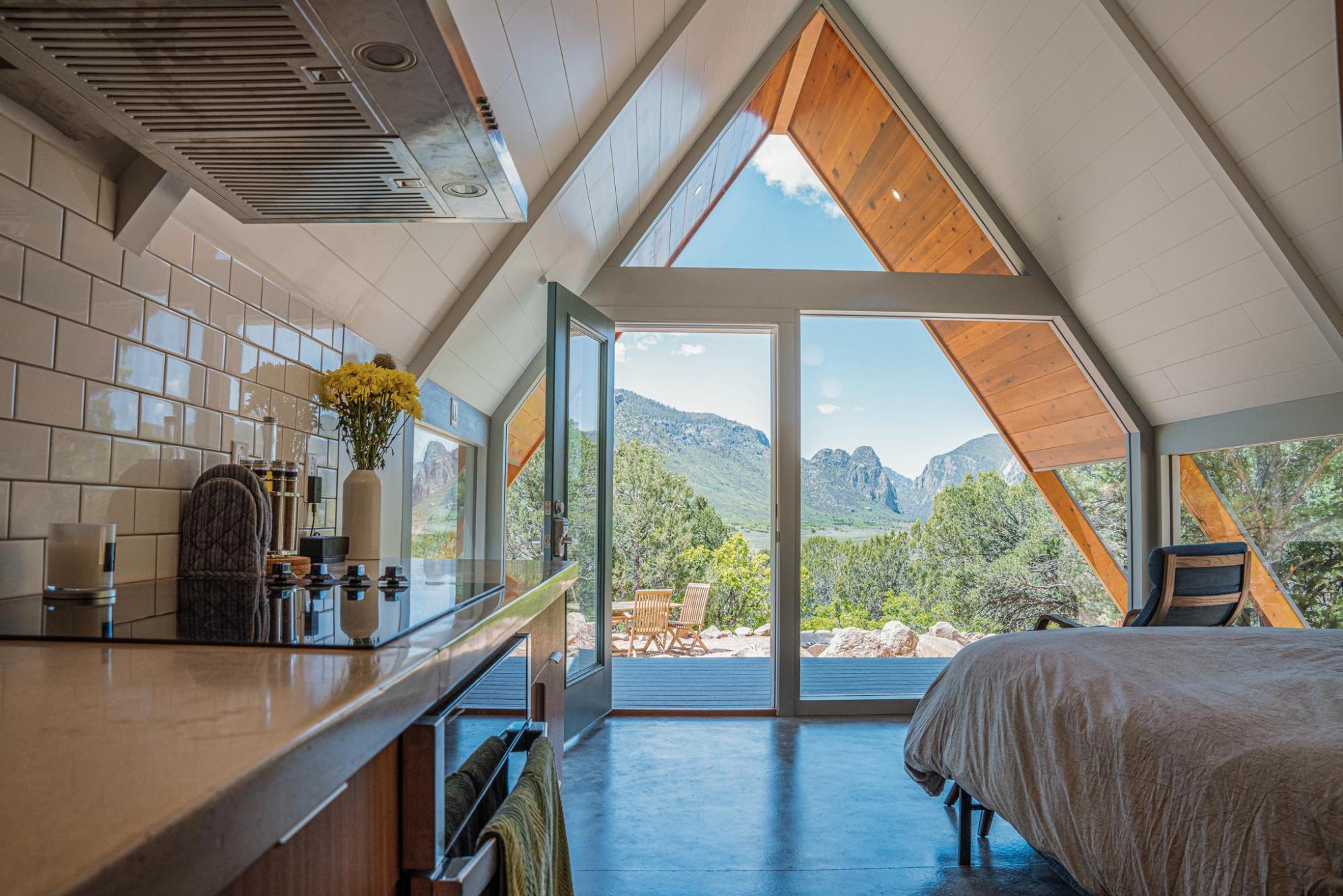 Chambre accueillante avec un lit et une vue panoramique sur des montagnes à travers la fenêtre